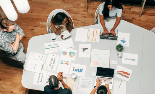 Team working around a table with documents, representing innovative collaboration